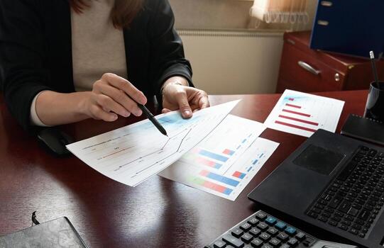 Rear view of female financial manager drawing various charts The image represents data-driven decision-making in business.and schemes on wall in office photo