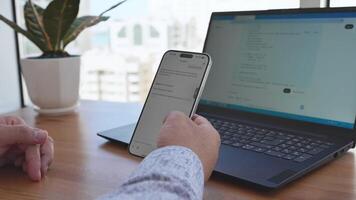 man använder sig av smartphone till skicka text meddelande på bärbar dator video