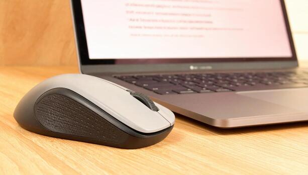 Close up ergonomic mouse beside laptop palm rest detail with copy space left modern computer accessory technology workspace design advertising background photo