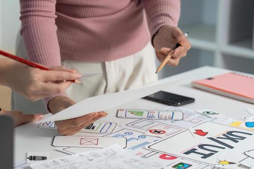 UX and UI Design Process. Close-up of hands reviewing sketches in a collaborative workspace. photo