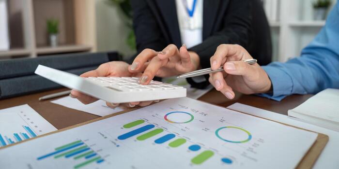 Data Analysis. Team members using calculator and charts for financial planning in a corporate setting. photo