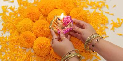 diwali celebracion. manos participación tradicional diya rodeado por maravilla flores foto