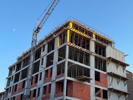 Concrete building under construction with crane and visible framework. Architecture, engineering, and urban development process in progress within a modern residential project. photo