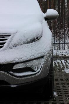 Headlight And Mirror Of Car Covered With Huge Layer Of Snow After Snowfall At Open Air Parking Area photo