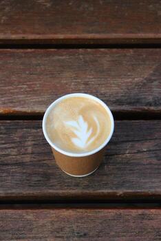 Mañana latté café en un arte taza con modelo en el espuma en un madera superficie foto