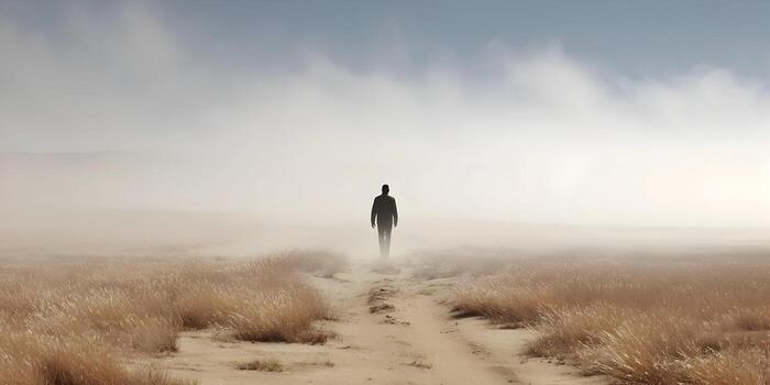 Man walks alone on a path through a foggy field photo