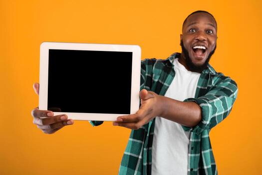 Great Application. Excited Black Guy Showing Tablet Computer With Empty Screen To Camera Recommending New App Posing Standing Over Yellow Studio Background. Digital Tablet Display Mockup For Advert photo
