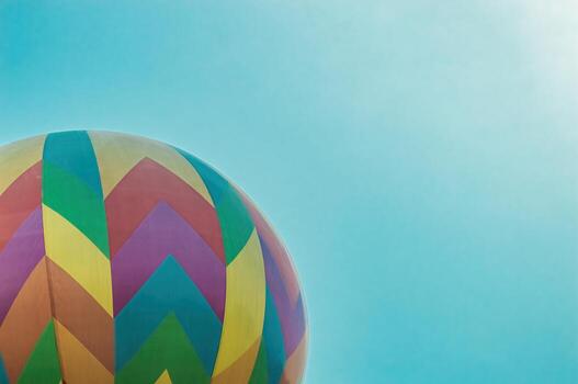 Close up of a colorful hot air balloon against a bright blue sky, featuring vibrant chevron patterns. Ideal for themes of travel, adventure, and summer fun, with copy space. photo