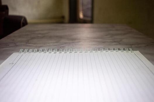 Close up of an open lined notebook with a spiral binding on a table, ready for notes, planning, or journaling in a bright interior. Represents organization, creativity, and study photo