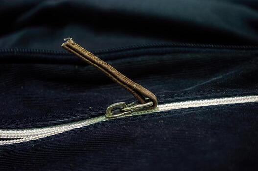 Close up on a black fabric with a zipper, featuring a brown leather pull tab. The zipper adds functionality and style to the material, suitable for various design projects photo