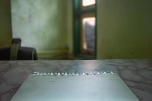Blank notepad on a marble desk with a blurred room backdrop, ideal for mockups. The scene suggests a quiet workspace, perfect for showcasing designs or messages on the notepad photo