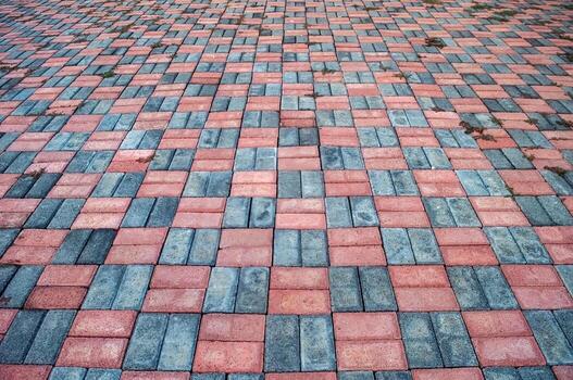Paving stone surface featuring a pattern of red and gray bricks. The interlocking brick arrangement creates a textured ground cover suitable for walkways and driveways. photo