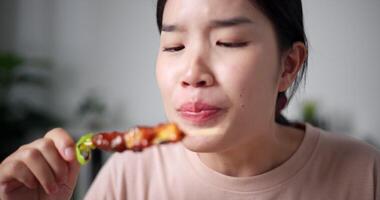 rilassato asiatico donna godendo mangiare grigliato barbecue al chiuso. fatti in casa cibo. mangiare con rilassamento video