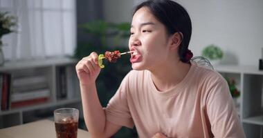 palmare sparo, rilassato asiatico donna godendo mangiare grigliato barbecue in casa video