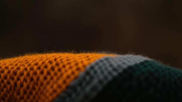 Textured fabric showcasing a vibrant pattern of orange, green, and gray threads in a warm setting photo