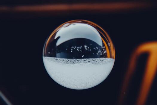 Bubble filled with liquid hovering above a surface during bright daylight photo