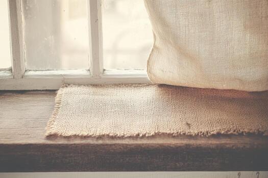 Sunlight streaming through window onto rustic burlap fabric on wooden sill photo