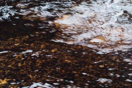 Clear water flowing over smooth stones in a serene natural setting photo