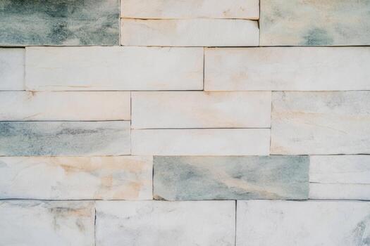 A textured wall made of large rectangular stones in shades of white and grey photo