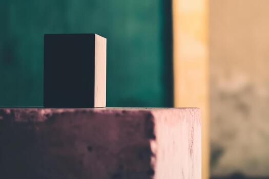 Black cube on a textured surface contrasting with a colorful background photo