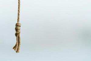 Close-up view of a knotted rope hanging against a blurred background photo