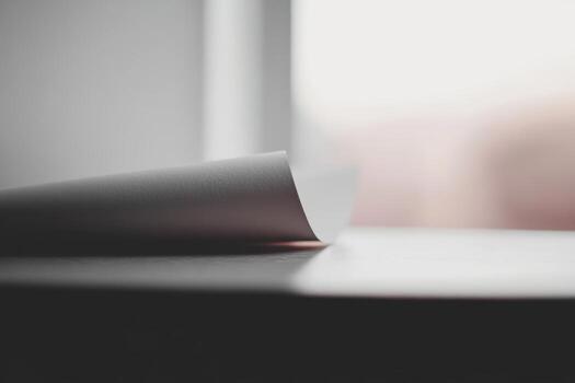 Close-up of curling paper on a table near a window with natural light photo