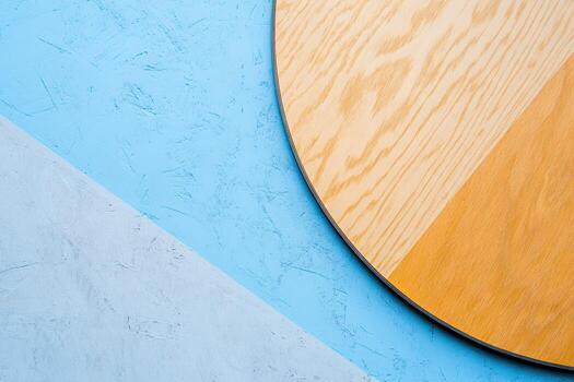 Modern round wooden table on a blue and gray textured background photo