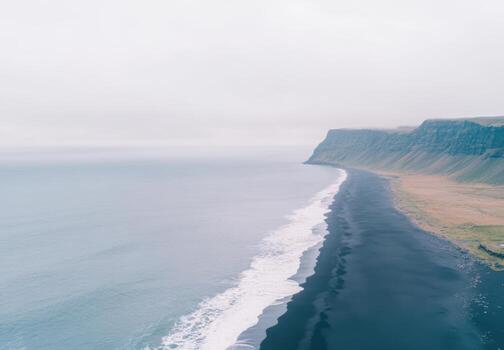 Coastal view showcasing black sand beach and cliffs under cloudy sky photo