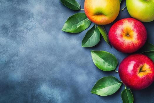 Vibrant apples with green leaves on textured blue background display photo