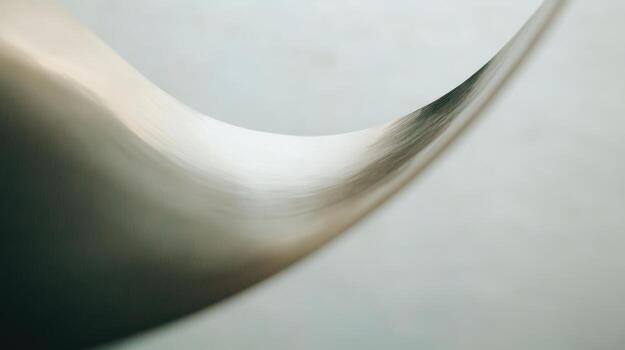 Curved metallic surface reflecting light in an abstract manner photo