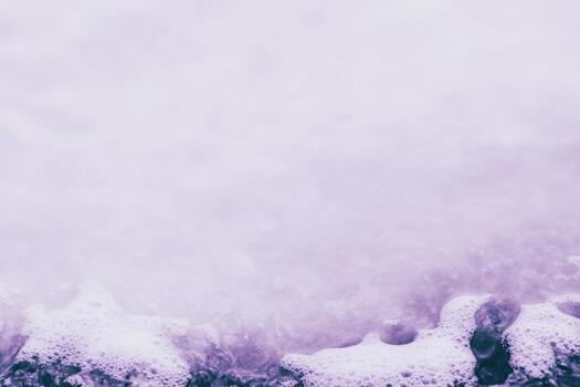 Waves crashing on the shore creating frothy details at sunset photo