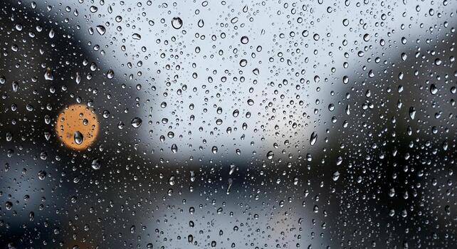 Raindrops on a window pane with blurred background, creating a serene and reflective mood during a rainy day. photo