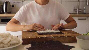 In this engaging tutorial, a woman demonstrates the art of sushi-making at home, skillfully preparing rice and rolling sushi with precision. Discover simple techniques to enjoy fresh sushi video