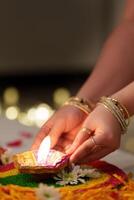 manos colocación diwali vela en vistoso rangoli foto