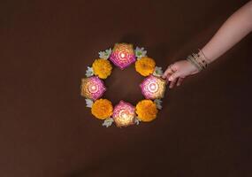 mano colocación diwali vela en floral arreglo foto
