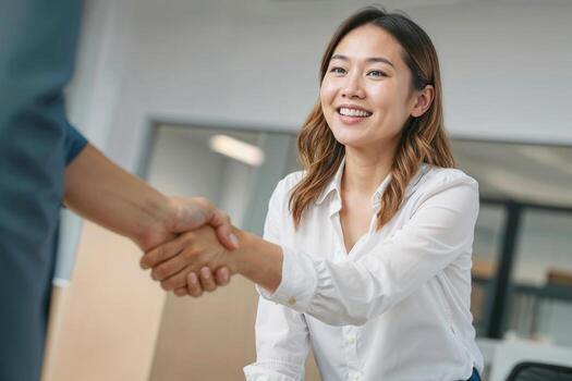 Asian woman shakes hands with a man in a business setting she is smiling and she is happy. Contract signing concept photo