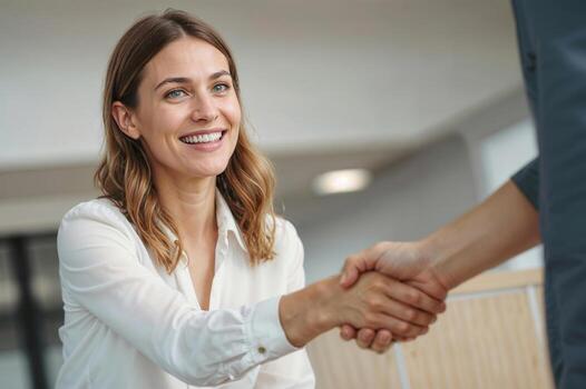 European woman real estate agent shakes hands with a man in a business setting she is smiling and she is happy. Contract signing concept photo