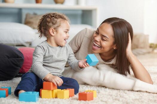 African American mother and daughter sit on the floor, smiling at each other while playing with toy blocks photo