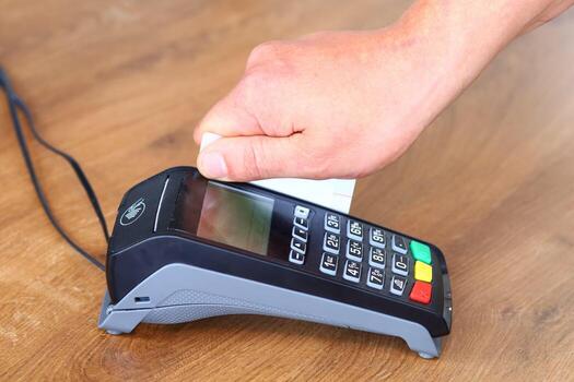 A person using a credit card reader on a wooden table photo