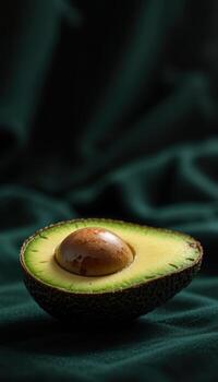 Half an Avocado on a Dark Green Fabric Background photo