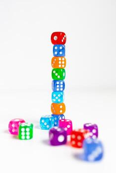 Colorful stack of multicolored dice on white background with scattered dice photo