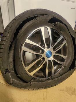 Broken car wheel with cracked rubber tire, dangerous damaged automobile equipment indoors. photo
