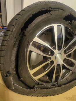 Automobile wheel with burst tire rubber, broken transportation part showing severe damage. photo