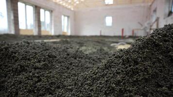 arbetare distribuera och nivå flytande skum betong och cement golv golv inuti en delvis konstruerad byggnad med stor fönster och trä- tak. video