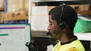 Customer support employee assisting clients in an industrial logistics hub, handling order mix up on e-commerce help line service. Black man resolving issues related to delivery delays. Camera B. video