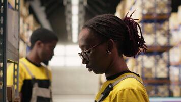 svart e-handel anställd läser in awb spårning tal, registrerar frakt etiketter och detaljer för de lager lager uppgifter. hantering pallar importera exportera operationer. kamera b. video