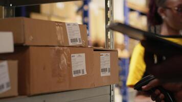 ung man använder sig av scanner på lådor streckkoder taggar i uppfyllelse Centrum. organiserad hyllor, paket etiketter och rutt planera Stöd effektiv distribution och sändning. logistik nav. kamera b. video