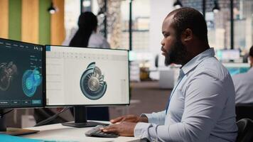 ingenieur in kantoor werken Aan wind turbine bestanddeel cad ontwerp, aan het doen eco vriendelijk energie Onderzoek. werknemer aan het doen digitaal modellering van wind energie generator een deel gebruik makend van pc programma, camera b video