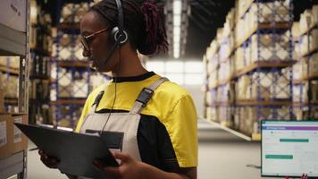 svart kvinna personal svar en kund service ring upp i en logistik nav, bistå med beställa spårning för paket, fixering en fel adress problem och uppdatering frakt detaljer. hjälp linje. kamera a. video