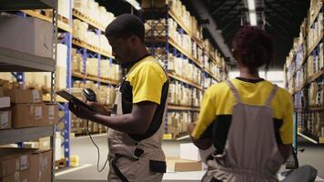 Erfüllung Center Arbeiter Scannen Versand Etiketten zu registrieren im Inventar, Aktualisierung Aufzeichnungen im Verwaltung System auf Tablette. E-Commerce Verkauf Lieferung Operationen im industriell Raum. Kamera a. video